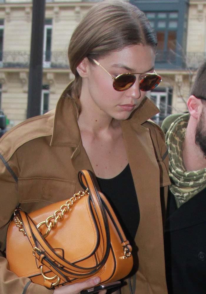 Gigi Hadid keeps her hair pulled back and her accessories understated as she arrives at the Four Seasons Hotel George V during Paris Fashion Week, carrying a caramel-colored Miu Miu Dahlia goatskin saddle bag that adds a warm contrast to her streamlined neutral-toned look