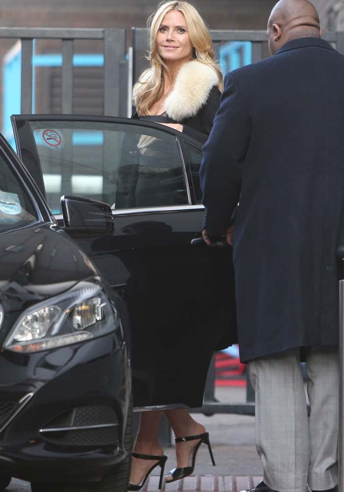 Heidi Klum steps out at ITV Studios in London wearing a black Noam Hanoch sheer dress with a fur-collar jacket and sleek black Jimmy Choo “Deckle” ankle-strap sandals