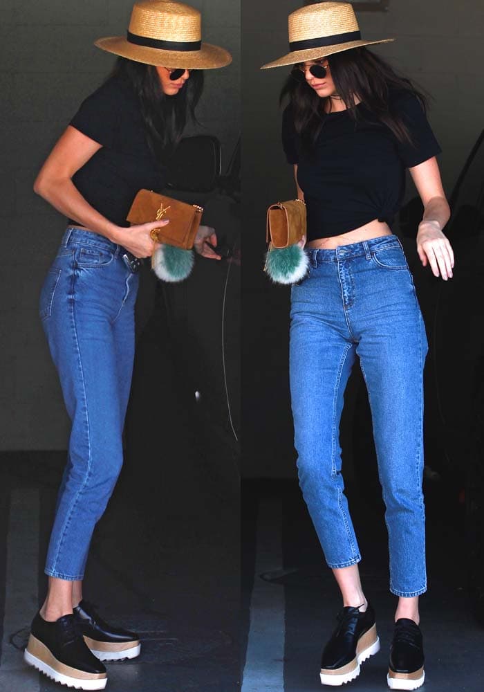 Kendall Jenner masters effortless off-duty style in a wide-brimmed straw hat, round sunglasses, a sleek black crop top, and high-waisted cropped denim, grounding the look with Stella McCartney platform oxfords while carrying a suede Saint Laurent clutch finished with a playful Fendi fur keychain