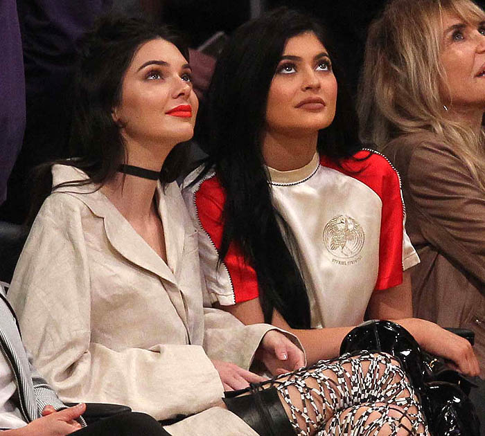 Kendall and Kylie Jenner sit courtside at the Lakers game, exuding effortless style with Kendall’s bold orange-red lipstick and Kylie’s sporty chic ensemble