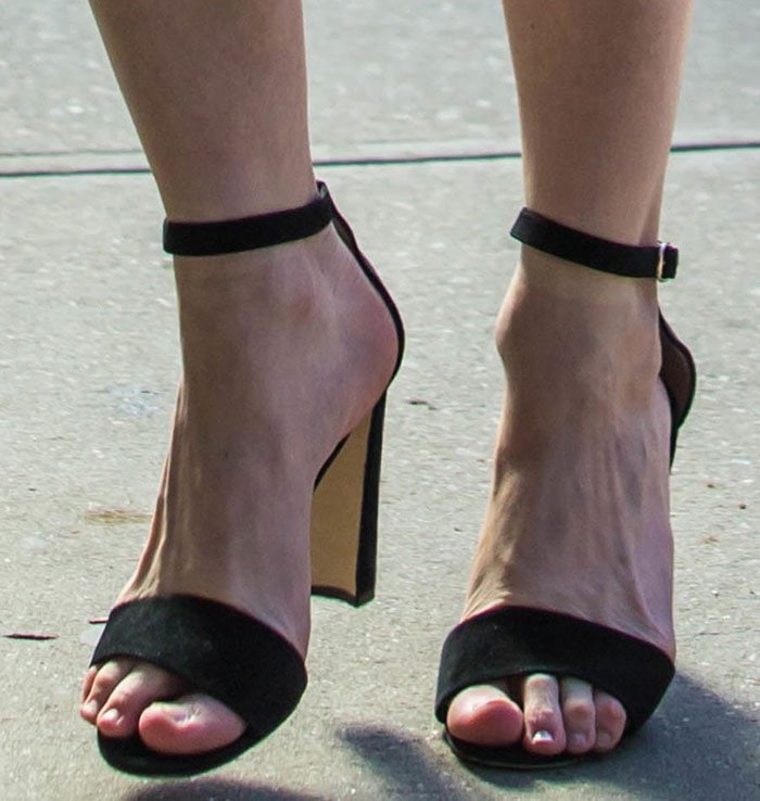 Kirsten Dunst’s feet take center stage in black Manolo Blahnik “Lauratopri” sandals, where slim ankle straps and a softly squared toe frame her pedicure while the sculptural half-moon block heel adds a modern, architectural finish