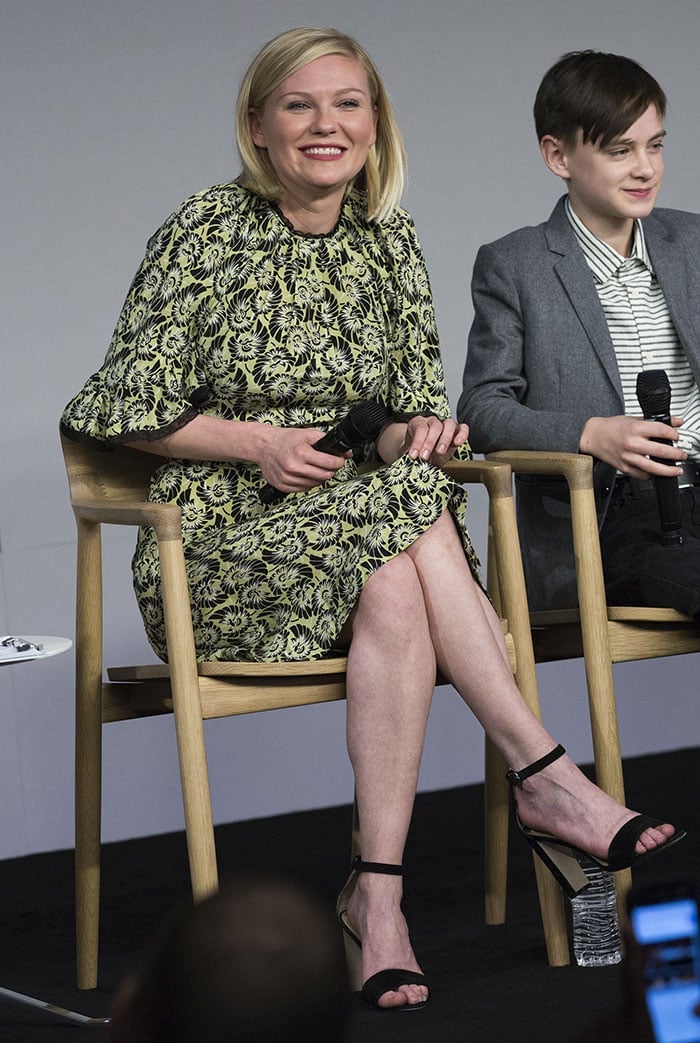 Kirsten Dunst keeps it effortlessly polished in a chartreuse floral dress, grounding the look with black Manolo Blahnik “Lauratopri” ankle-strap sandals that subtly elongate her silhouette
