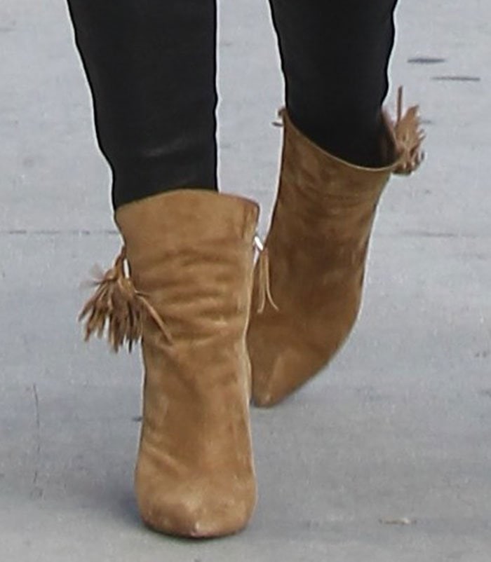 Lily Aldridge’s feet in tan Isabel Marant “Leyton” suede ankle boots, featuring pointed toes, stacked heels, and tassel-embellished side details