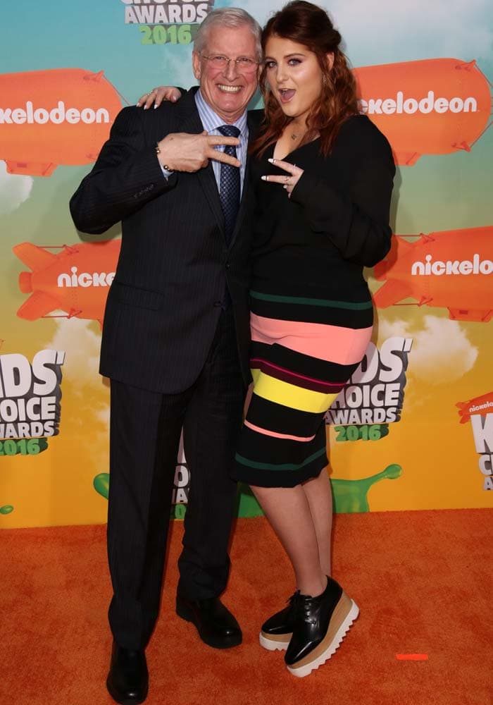 Meghan Trainor and her dad Gary flash peace signs from the orange carpet of the Nickelodeon Kids' Choice Awards