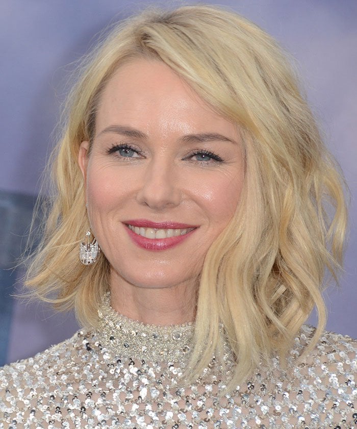 Naomi Watts wears loose, side-parted waves, softly defined eye makeup, pink lipstick, and Solange Azagury-Partridge chandelier earrings with her sparkling Derek Lam Fall 2016 ensemble