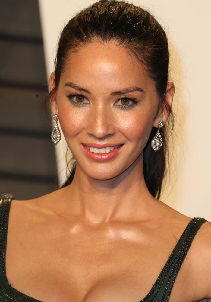 Olivia Munn turns to reveal the sleek, body-contouring silhouette of her embroidered J. Mendel gown, paired with a polished high ponytail and diamond drop earrings