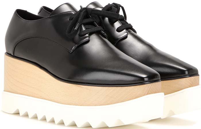 A pair of Stella McCartney–style Elyse platform oxfords, featuring a sleek black faux-leather Derby upper set atop a chunky, saw-edge wooden and rubber sole for a bold yet polished statement