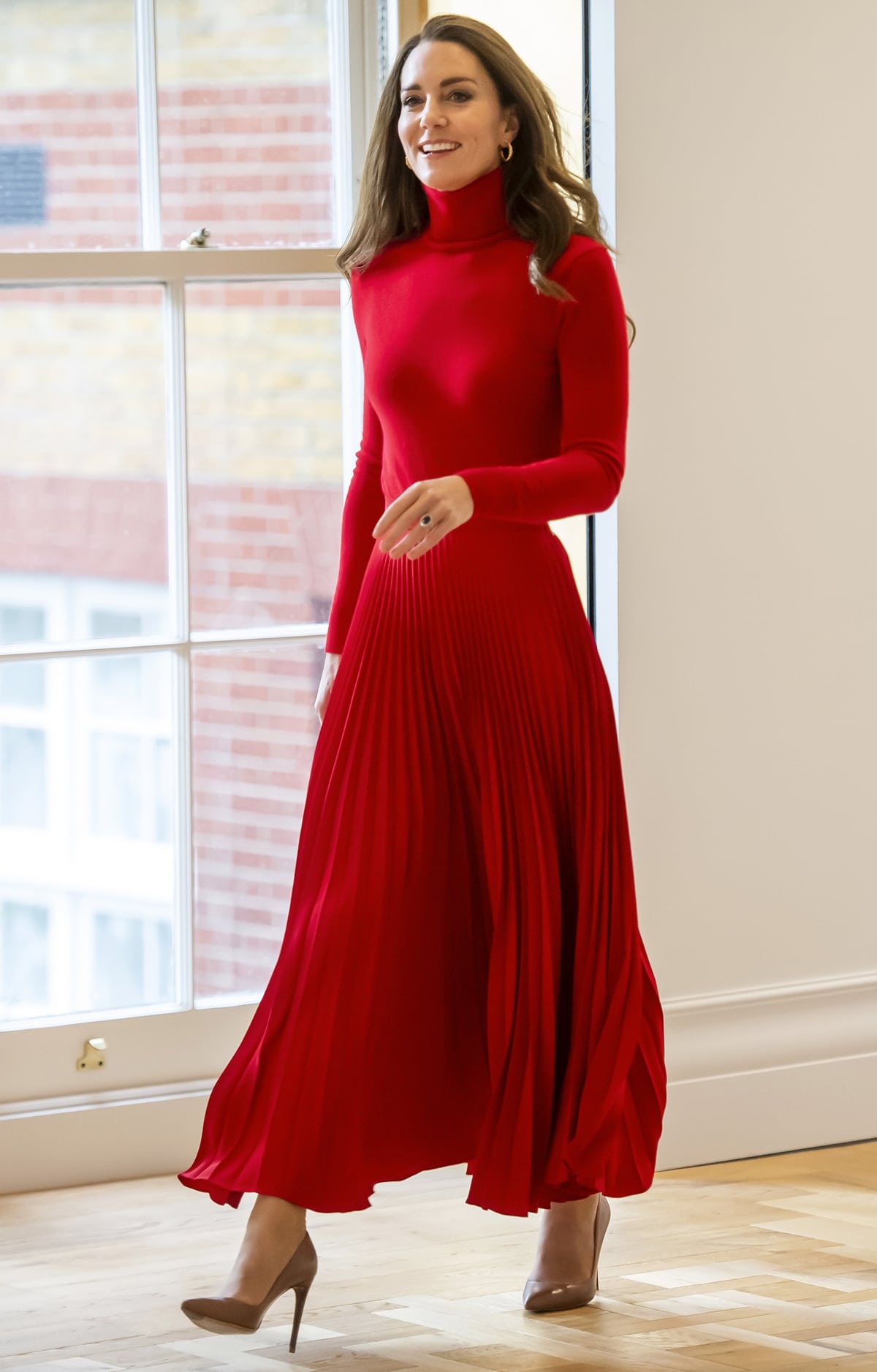 The Duchess of Cambridge styled a monochrome red look with a Ralph Lauren turtleneck, a pleated Christopher Kane skirt, and pointed-toe pumps that kept the bold outfit polished and streamlined