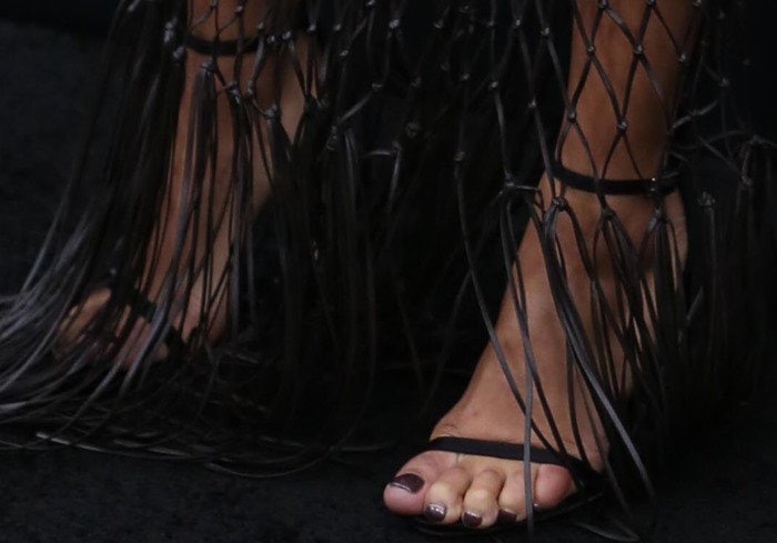 Her look was finished with classic black Stuart Weitzman “Nudist” sandals peeking through the dress’s dramatic fringe detailing