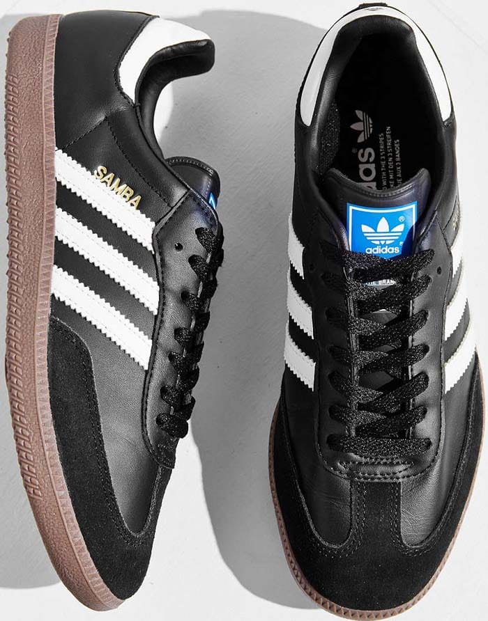 The Adidas Originals Samba is shown in detail, featuring smooth black leather, suede overlays, and signature white stripes that define the enduring silhouette