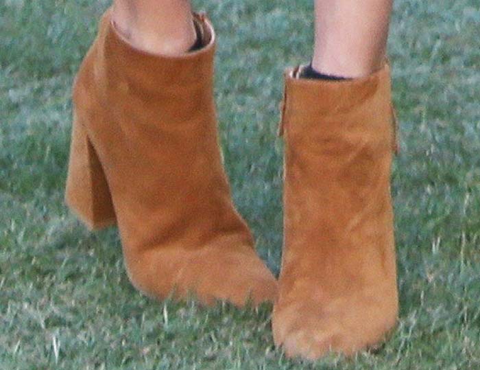 A closer look at Alessandra Ambrosio’s tan suede ankle boots reveals a chunky block heel that adds height while staying practical for walking on grass