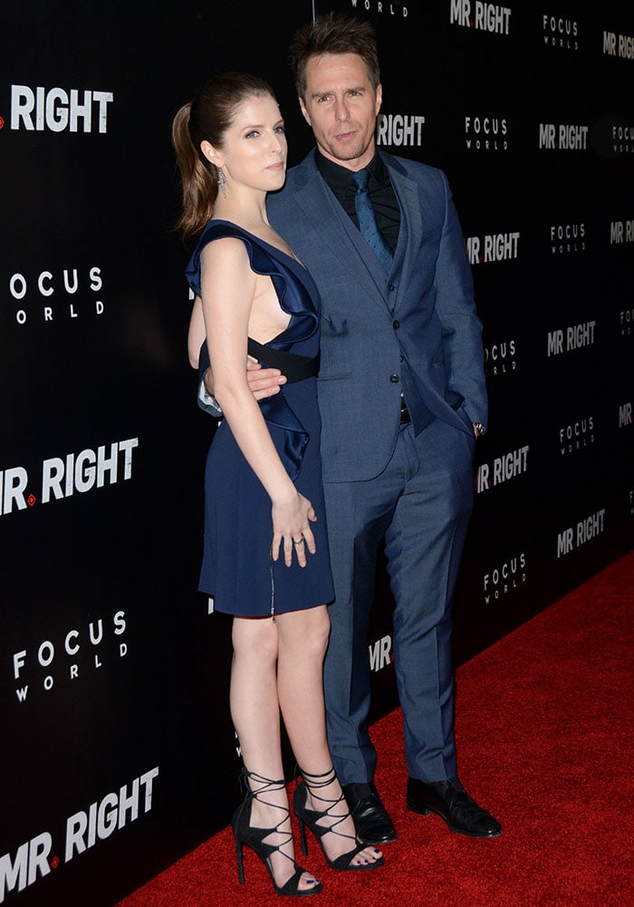Anna Kendrick shares a playful red-carpet moment with co-star Sam Rockwell, pairing her navy David Koma mini with Stuart Weitzman’s lace-up “LegWrap” sandals