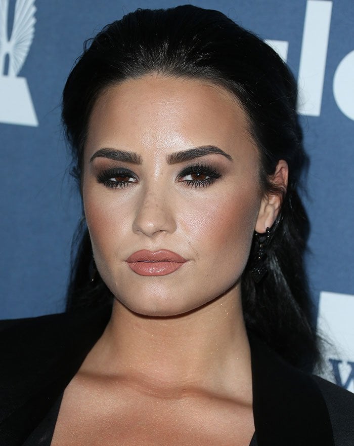 Smoky eyes, nude lips, and a sleek half-up hairstyle complemented the monochromatic elements of Demi Lovato's striking awards-show ensemble