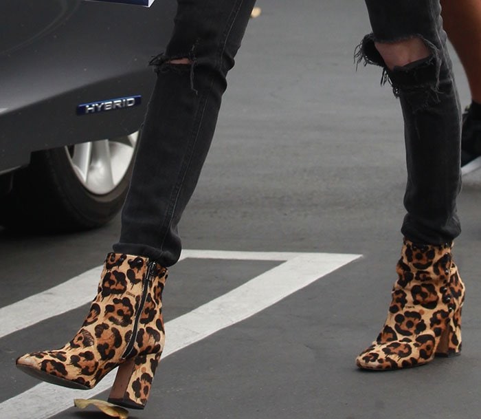 Emma Roberts styles her leopard-print calf hair Coach “Felicia” boots with black skinny jeans, creating a seamless, leg-lengthening silhouette that highlights the bold block heels