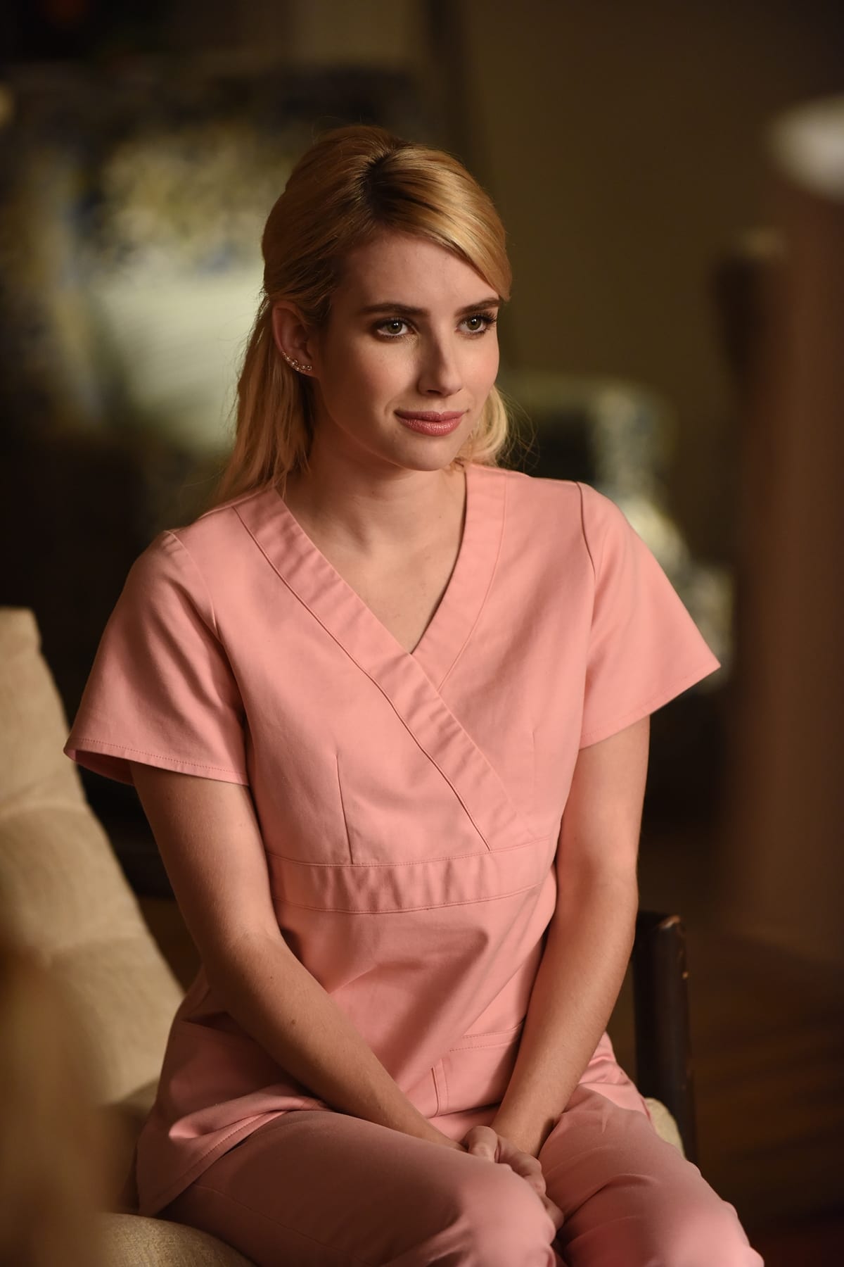 Emma Roberts as Chanel Oberlin in Scream Queens, balancing her sorority queen persona with a deceptively sweet look in bubblegum-pink scrubs—proof that even in camp horror, her style moments became instantly iconic