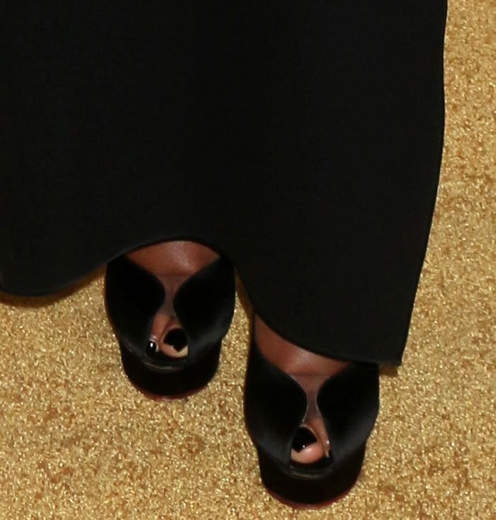 A rare front glimpse of the Charlotte Olympia “Daphne” pumps shows the peep-toe opening and exaggerated island platform peeking out from under the gown