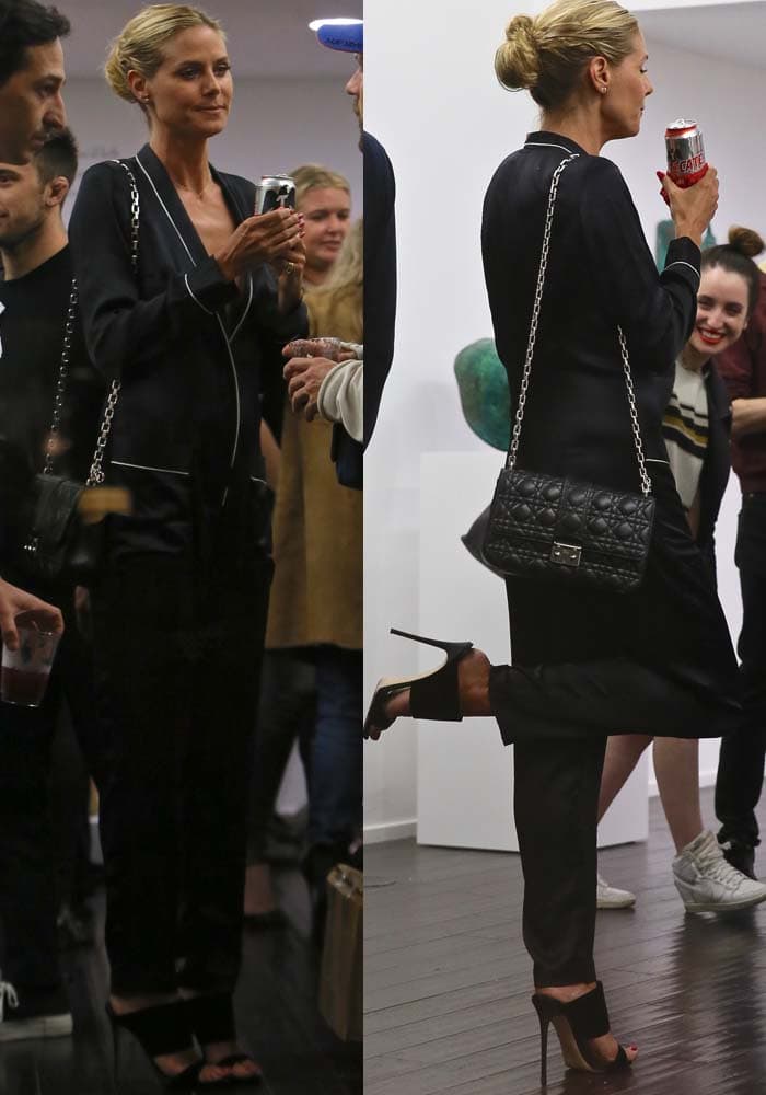 Heidi Klum elegantly sips a Tecate, showcasing her relaxed yet chic style in a Fleur du Mal silk jumpsuit, complemented by her quilted Miss Dior chain flap bag and Giuseppe Zanotti mules