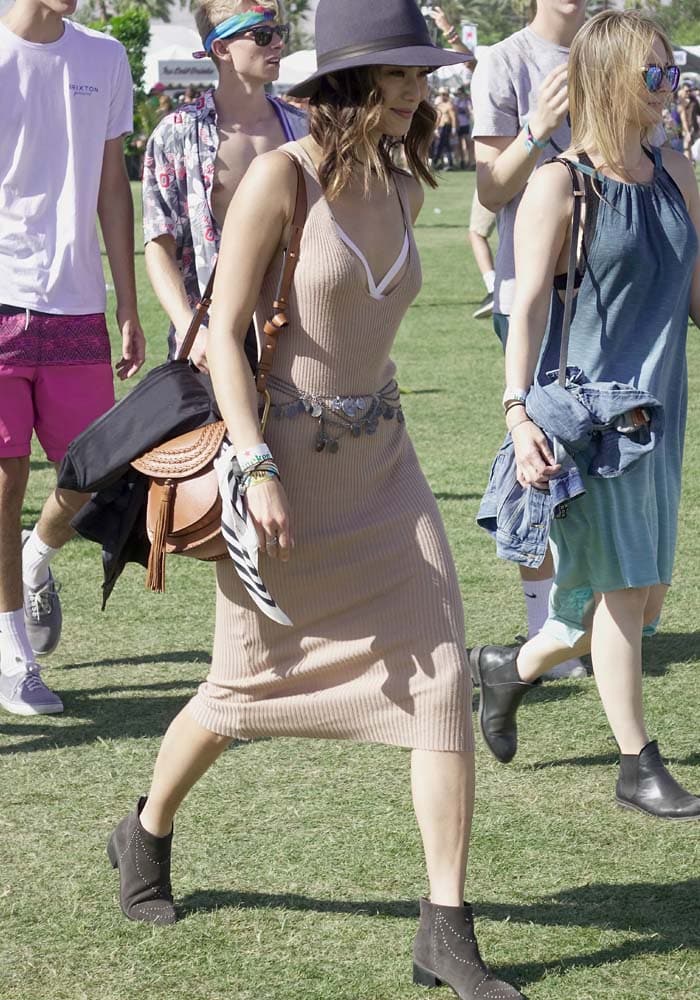 Jamie Chung styled a ribbed knit midi dress with studded Grey City “Wendy” ankle boots, a wide-brim hat, and layered festival accessories while walking the Coachella grounds