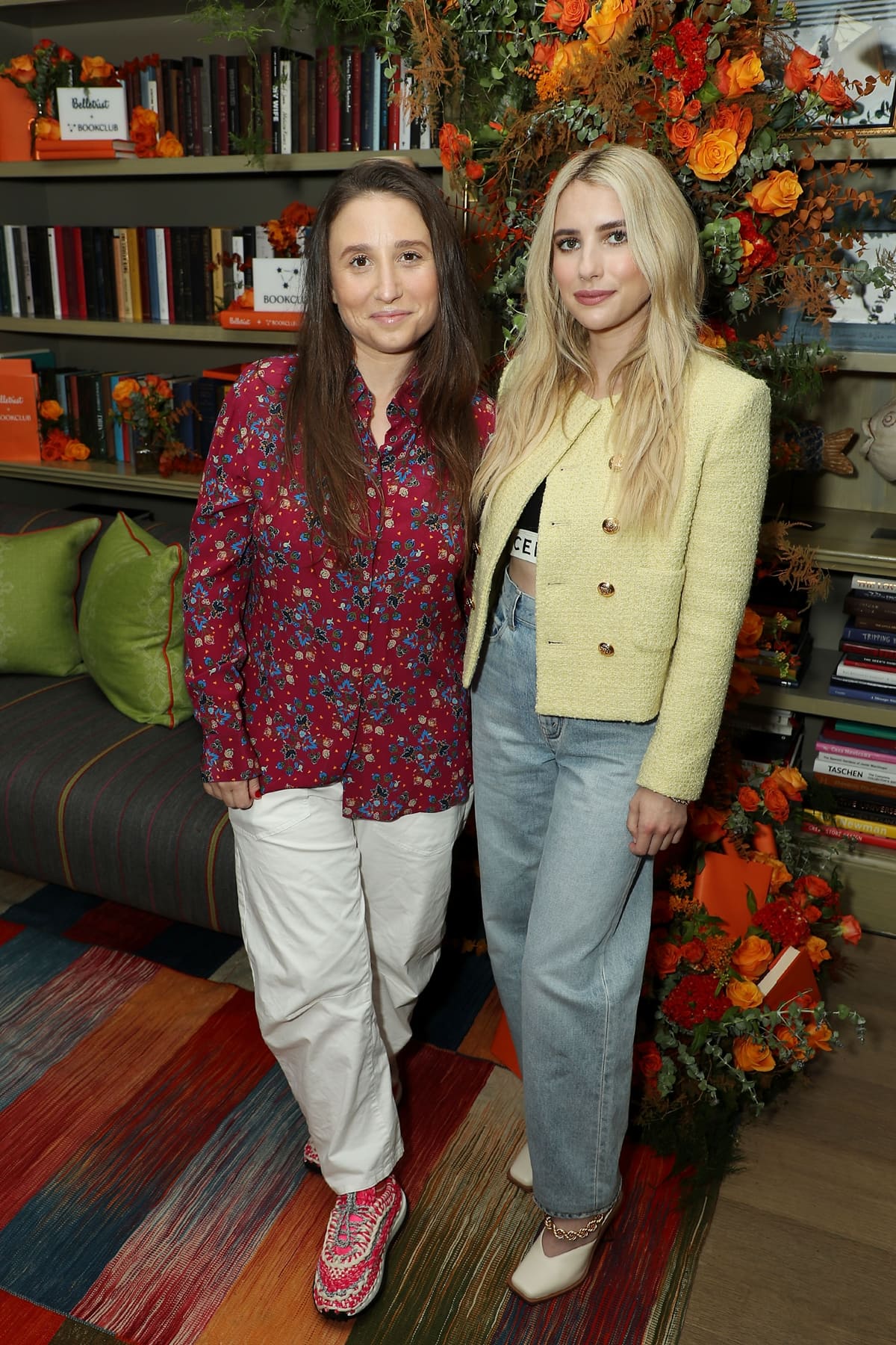 Karah Preiss and Emma Roberts at the Belletrist book club launch in New York City on July 27, 2021—Roberts in a cropped Celine top, yellow tweed blazer, relaxed jeans, and chain-strap white pumps that added a refined edge to her casual-chic ensemble