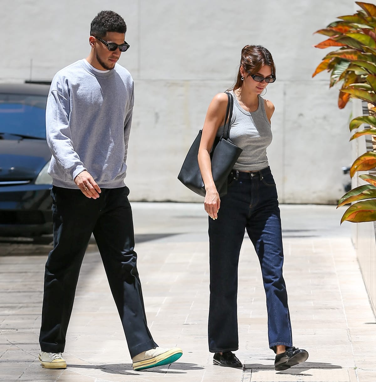 Kendall Jenner steps out in her signature model-off-duty uniform—sleek black loafers grounding straight-leg denim and a fitted gray tank—alongside Devin Booker during a low-key Los Angeles outing