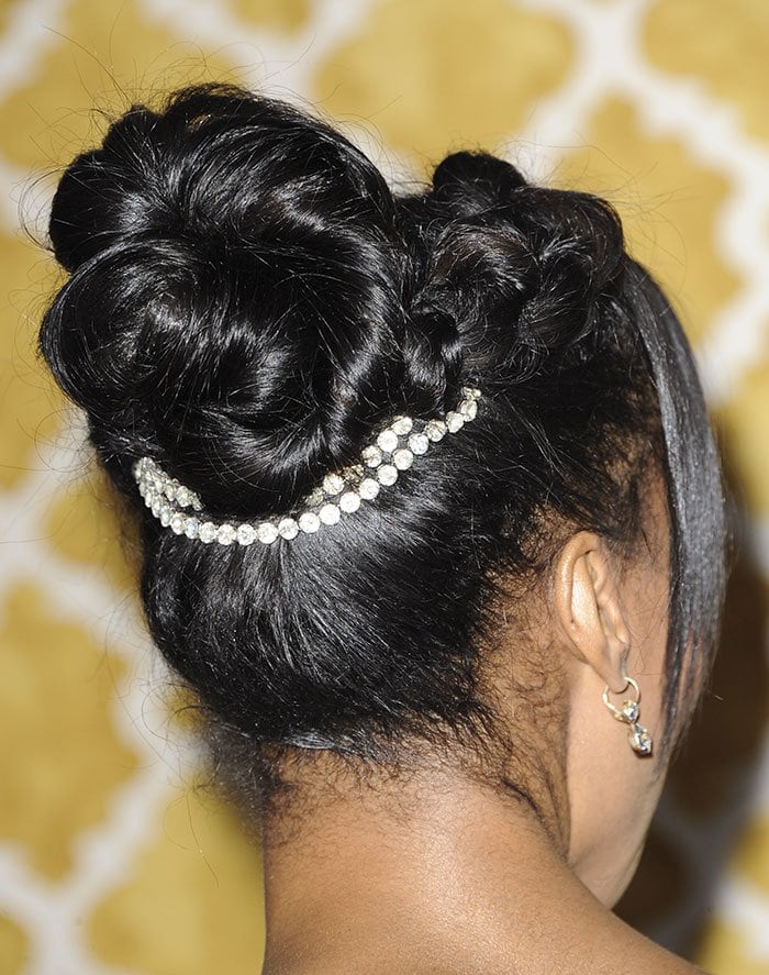 Her intricate updo, finished with a delicate jeweled band, adds a refined, almost vintage-inspired touch that complements the romantic floral pattern of the gown
