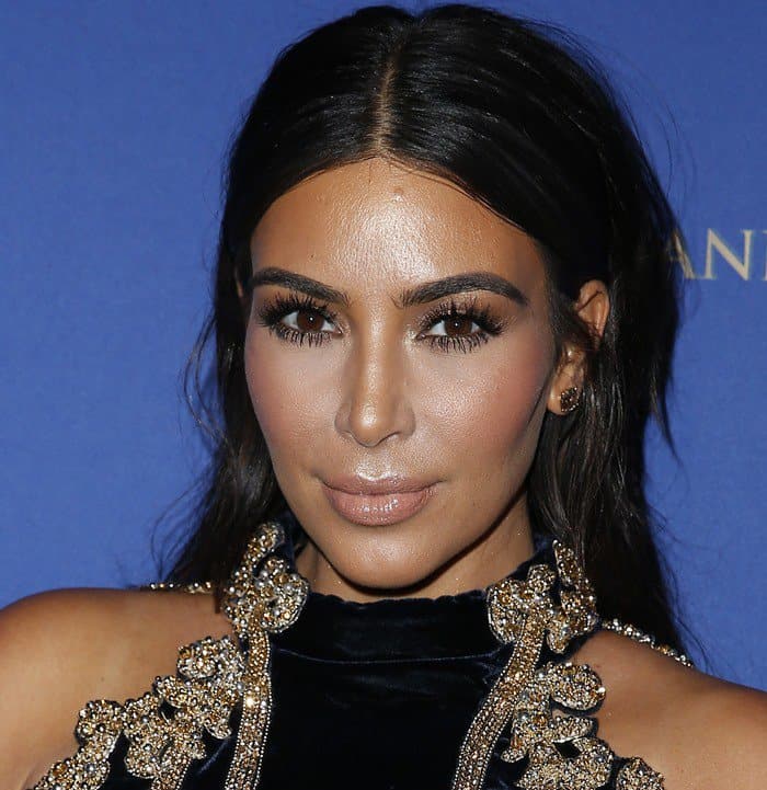 Kim Kardashian kept her glam polished with bronze-toned makeup, dramatic lashes, and sleek center-parted hair that highlighted her sculpted features