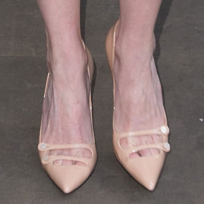 A closer look at her Gucci “Aneta” pumps reveals glossy nude patent leather, a sharply pointed toe, and delicate double vamp straps accented with pearl buttons