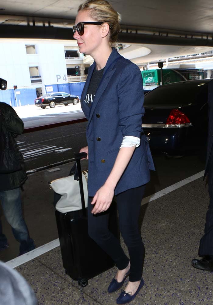 Kirsten Dunst keeps it effortlessly polished at LAX in a navy blazer layered over a casual tee and skinny jeans, rolling her luggage with understated ease
