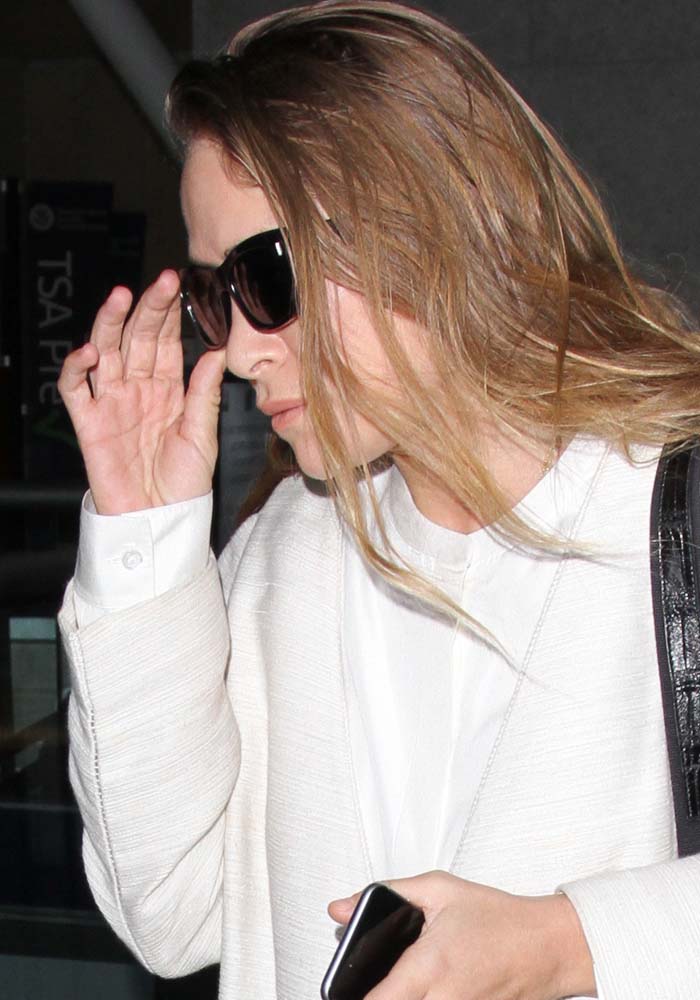 Mary-Kate Olsen shields her eyes behind Oliver Peoples × The Row 71st Street sunglasses while arriving at LAX on April 2, 2016, wearing an ivory textured coat and crisp white blouse