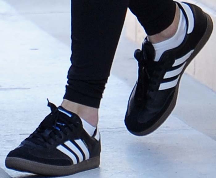 A close-up highlights the black-and-white Adidas Samba sneakers, finished with a gum sole that underscores their timeless appeal beyond the football pitch