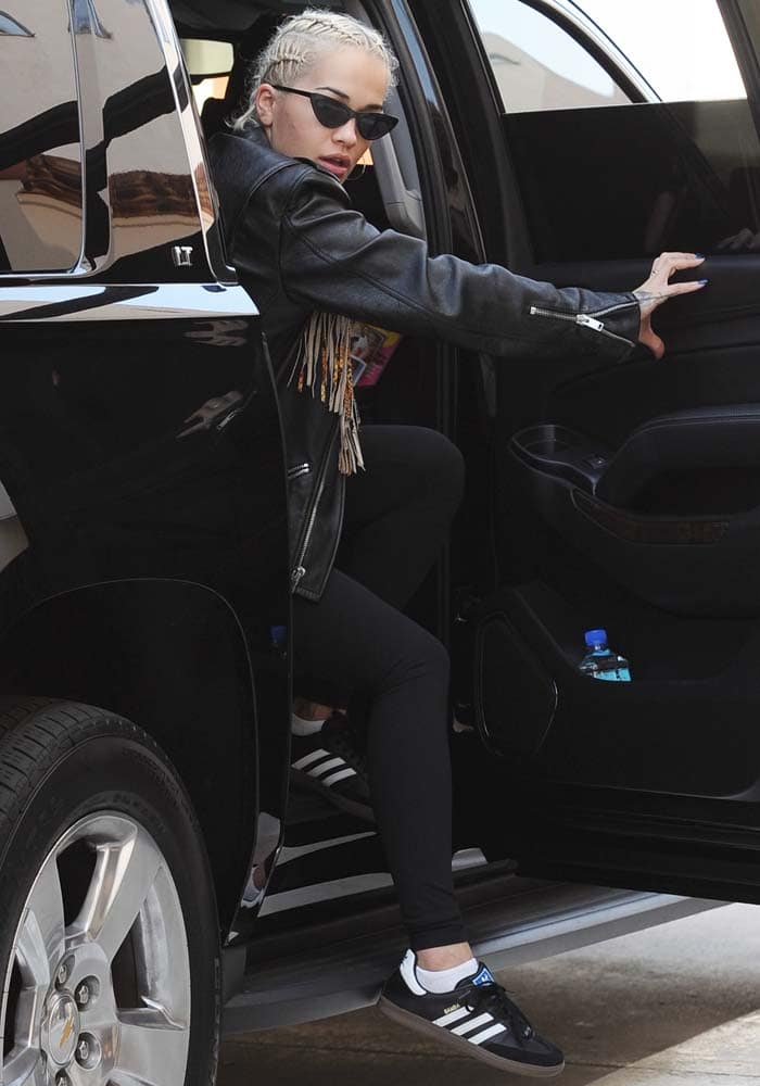 Rita Ora exits her vehicle in a sleek athleisure look, pairing cornrow braids, sharp cat-eye sunglasses, and Adidas Sambas for an effortlessly cool off-duty moment