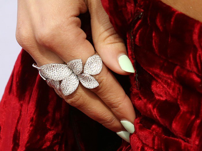 Zendaya paired an oversized diamond butterfly ring by Pasquale Bruni with a soft mint-green manicure, adding a fresh pop of color against the rich crimson velvet of her Haider Ackermann suit