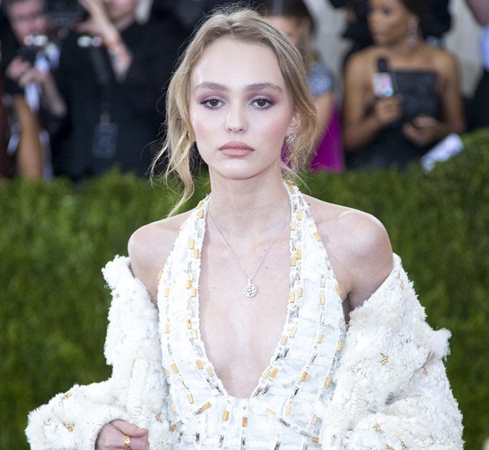 Lily-Rose Depp shines with soft pink eyeshadow, a natural updo, and a delicate silver pendant necklace, perfectly complementing her ethereal beauty at the 2016 Met Gala