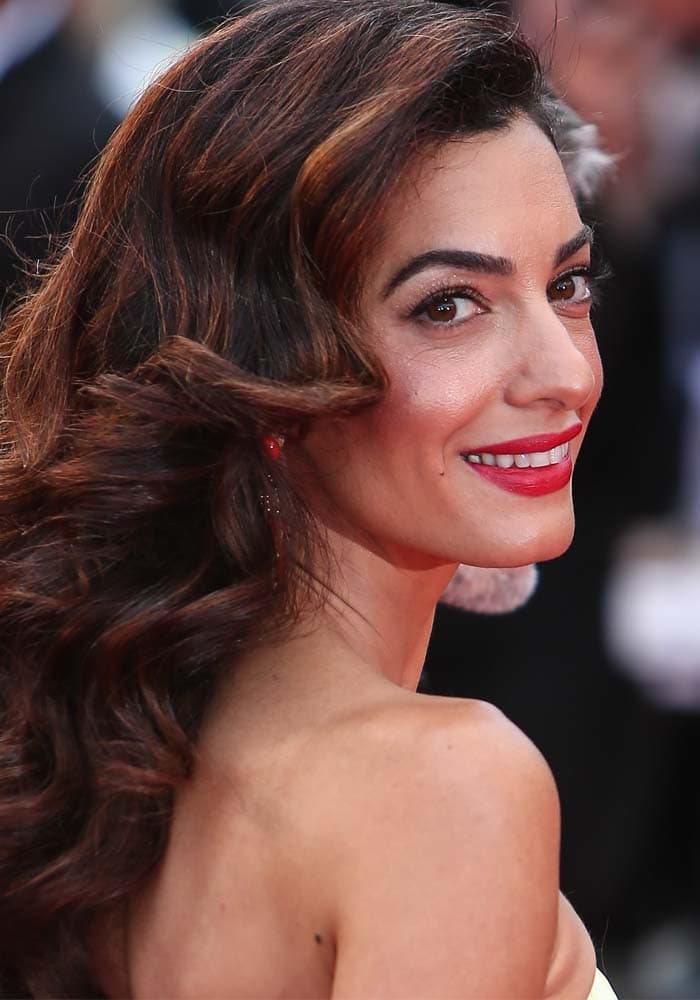 Amal Clooney radiates elegance in flowing dark curls and a bold red lip as she graces the Cannes Film Festival red carpet in a strapless gown