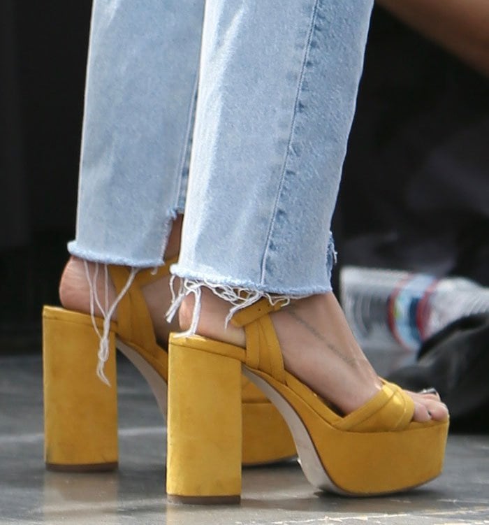Ashley Tisdale adds major height with bold yellow suede platform sandals featuring thick crossover straps and chunky block heels that boost her frame by over 4 inches