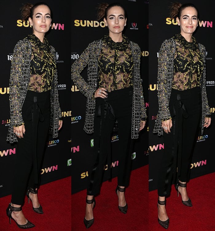 She balances masculine tailoring and romantic detailing in high-waisted tuxedo pants and a sheer floral blouse, anchored by sculptural mesh pumps