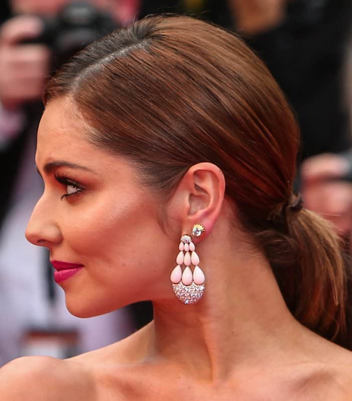 The chandelier earrings shimmer with 18 soft pink opals and 258 diamonds, their layered drops catching the light against a sleek, pulled-back hairstyle on the red carpet