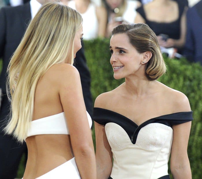 Emma Watson shares a candid moment in her black and white off-the-shoulder Calvin Klein ensemble at the 2016 Met Gala