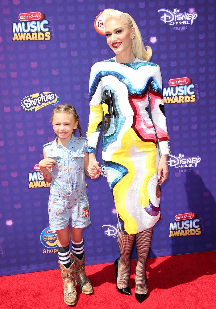 Stella Stefani brought a playful, kid-friendly contrast to Gwen's high-fashion look in a light blue printed romper, striped knee-high socks, and well-worn cowboy boots that added a touch of Western charm to the Radio Disney Music Awards red carpet