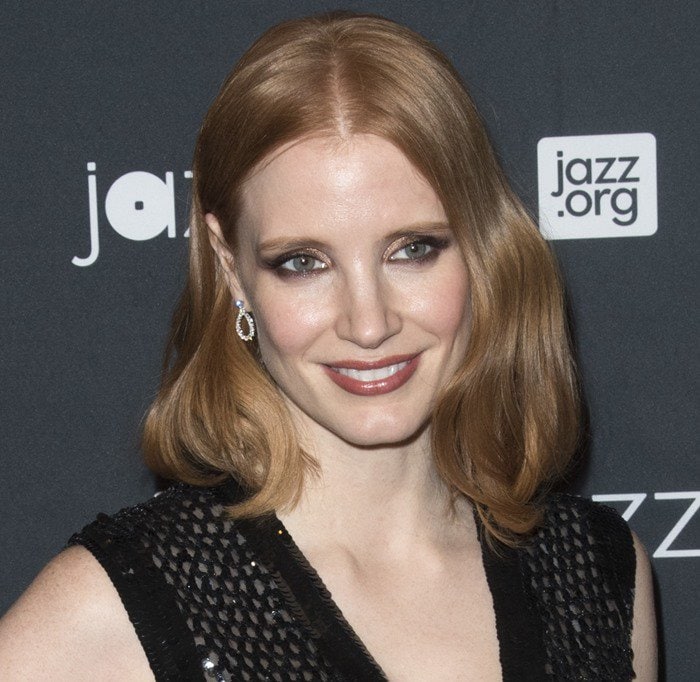 Jessica Chastain complements her red-carpet look with soft mauve lipstick and smoky, charcoal-toned eye makeup, highlighting her signature auburn hair and luminous complexion