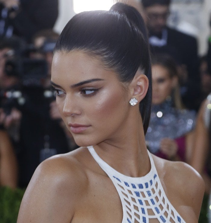 Kendall Jenner exudes futuristic elegance with a sleek ponytail, bronzed glow, and sculpted makeup that perfectly complements her tech-inspired Versace gown at the 2016 Met Gala