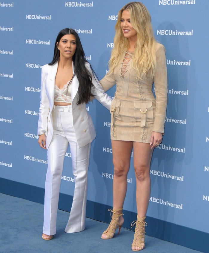 Kourtney Kardashian joined Khloé on the NBCUniversal blue carpet, contrasting an all-white tailored suit with Khloé's military-inspired Balmain ensemble