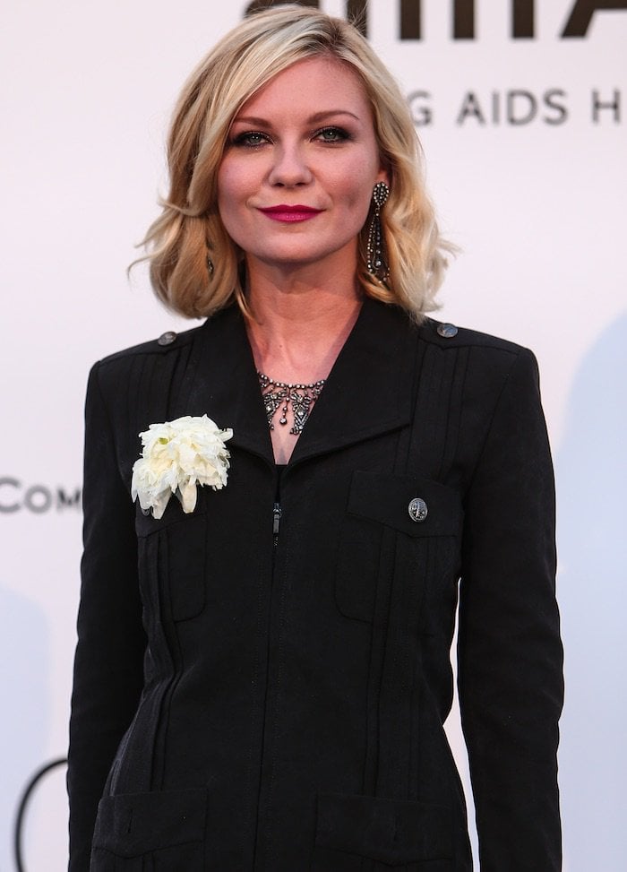 Kirsten Dunst balances classic Chanel tailoring with soft femininity, her white camellia brooch and vintage-inspired Fred Leighton jewels adding depth to the structured black ensemble