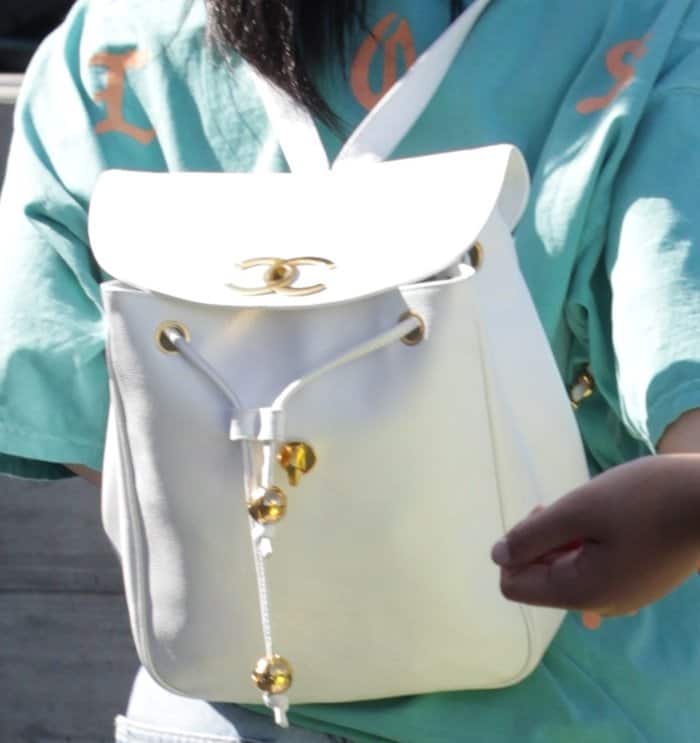 Kylie Jenner's white vintage Chanel backpack featuring a drawstring closure with gold-tone hardware, a tonal designer logo detail, a rear zip pocket, and two leather shoulder straps