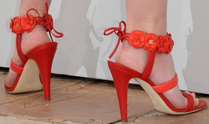 This detailed shot highlights Lily-Rose Depp's vibrant red Chanel sandals, featuring distinctive floral embellishments on the ankle straps