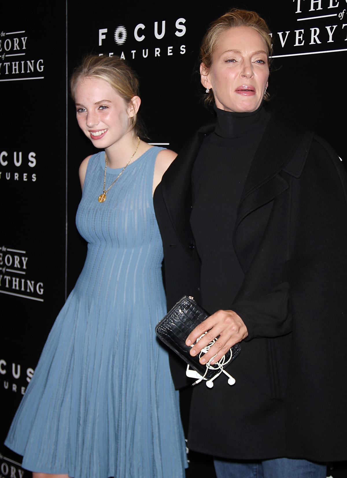 Maya Thurman-Hawke looks youthful in a sleeveless powder-blue pleated dress, while Uma Thurman opts for chic minimalism in a black turtleneck and coat at the 2014 New York premiere of The Theory of Everything
