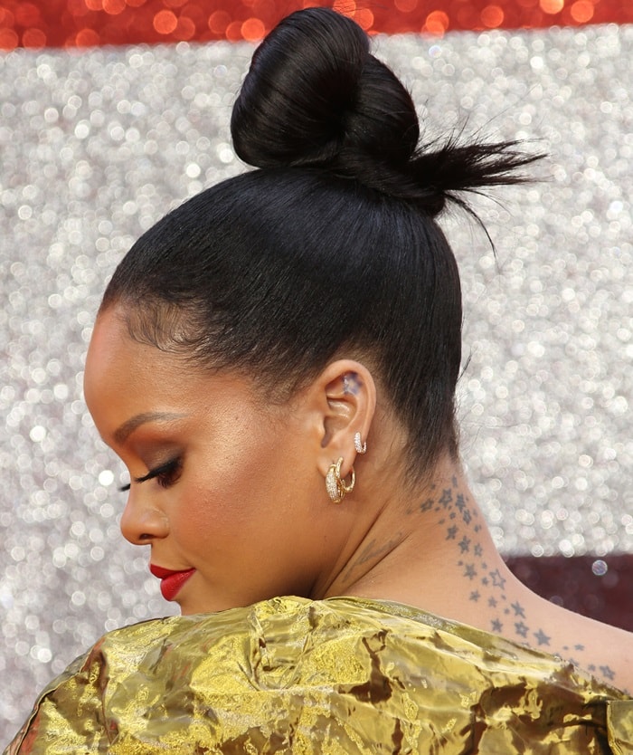 Rihanna elegantly highlights her signature neck and upper back star tattoos, inked in 2008, perfectly complementing her glamorous gold ensemble