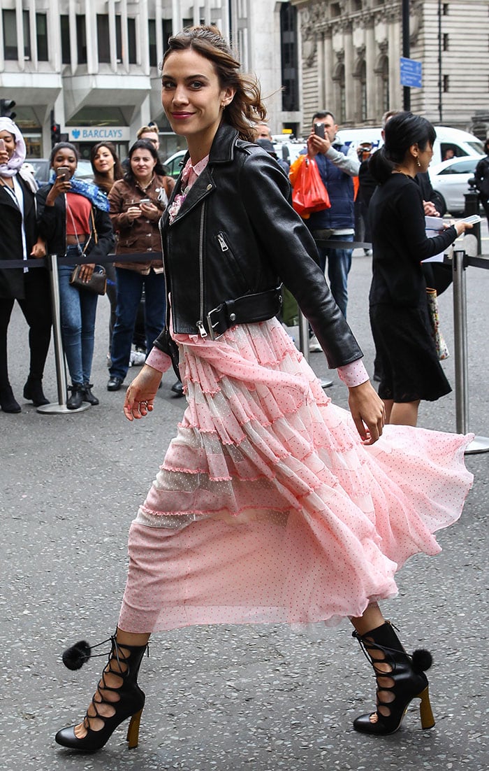 Alexa Chung strikes the perfect balance of edgy and romantic in a frilly pink Gucci dress styled with a cropped leather biker jacket and lace-up “Heloise” boots