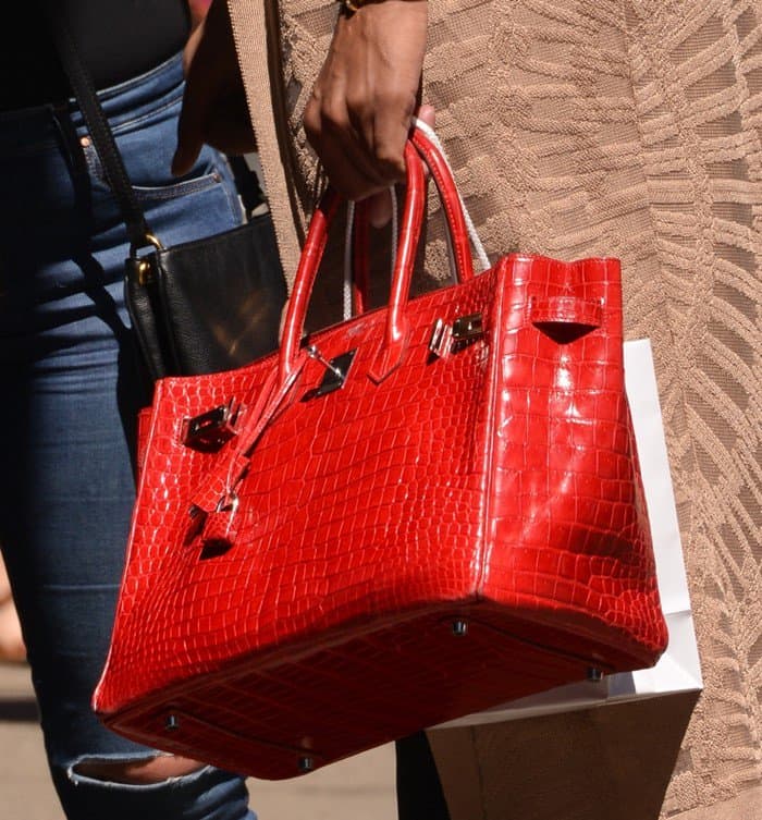 EJ Johnson carries a striking red Hermès Crocodile Birkin—an ultra-luxurious handbag estimated to cost around $100,000, exuding status and sophistication