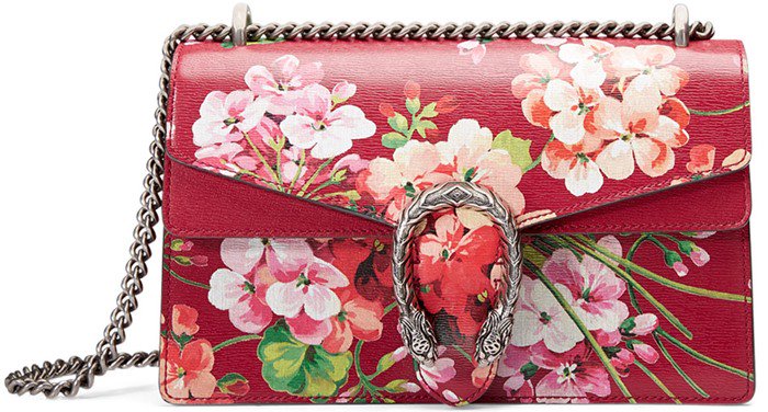Gucci’s “Dionysus Blooms” shoulder bag stands out with its vibrant floral print, signature textured tiger-head clasp, and antique silver chain strap